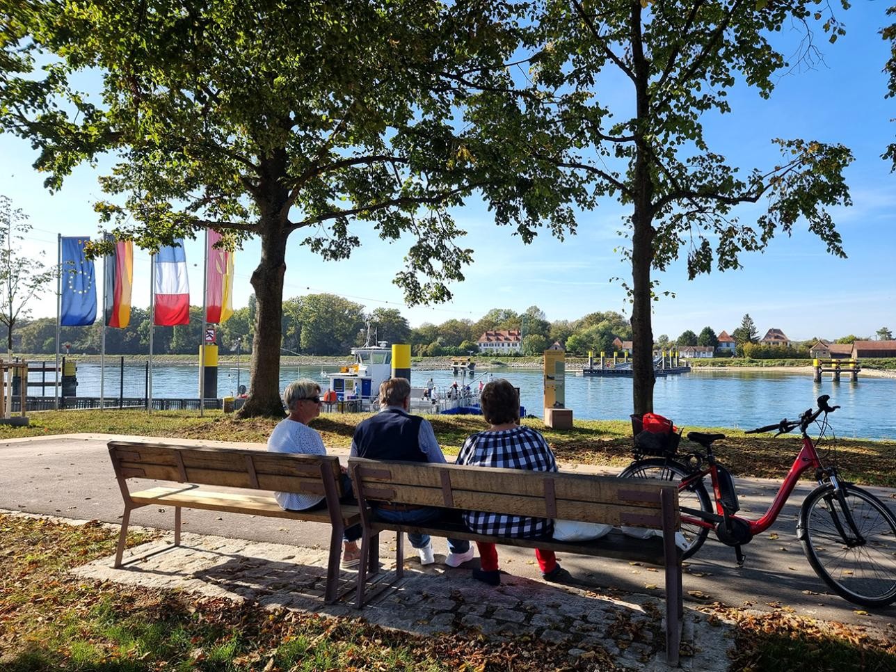 People sitting on a bench on the Rhine promenade in Plittersdorf
