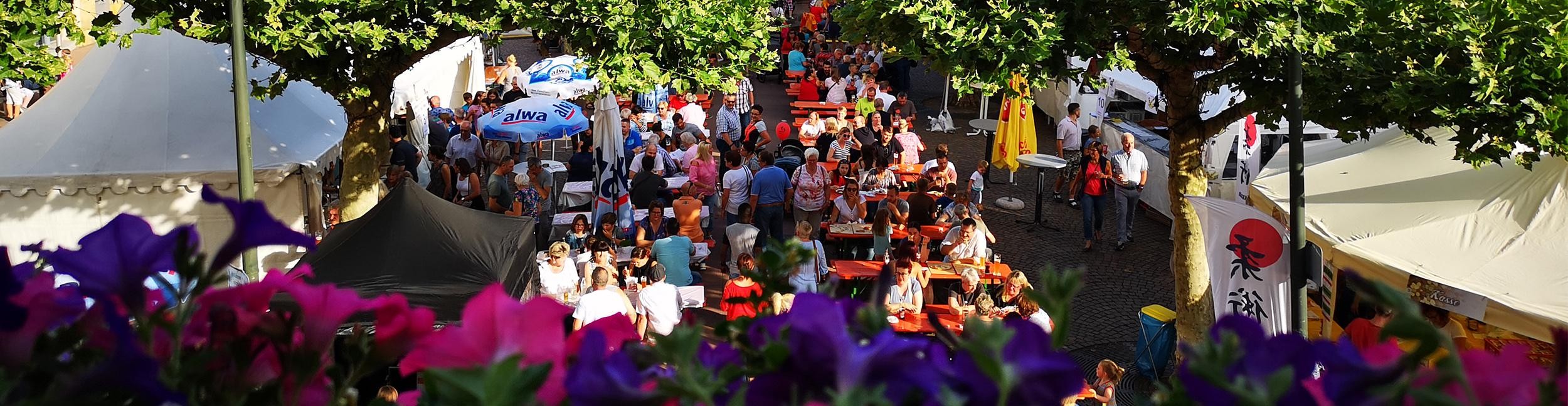 Stadtfest in Rastatt: 25. bis 27. Juli 2025. Foto: Stadt Rastatt/Isabelle Joyon Menschen sitzen auf Bierbänken auf dem Marktfest beim Stadtfest